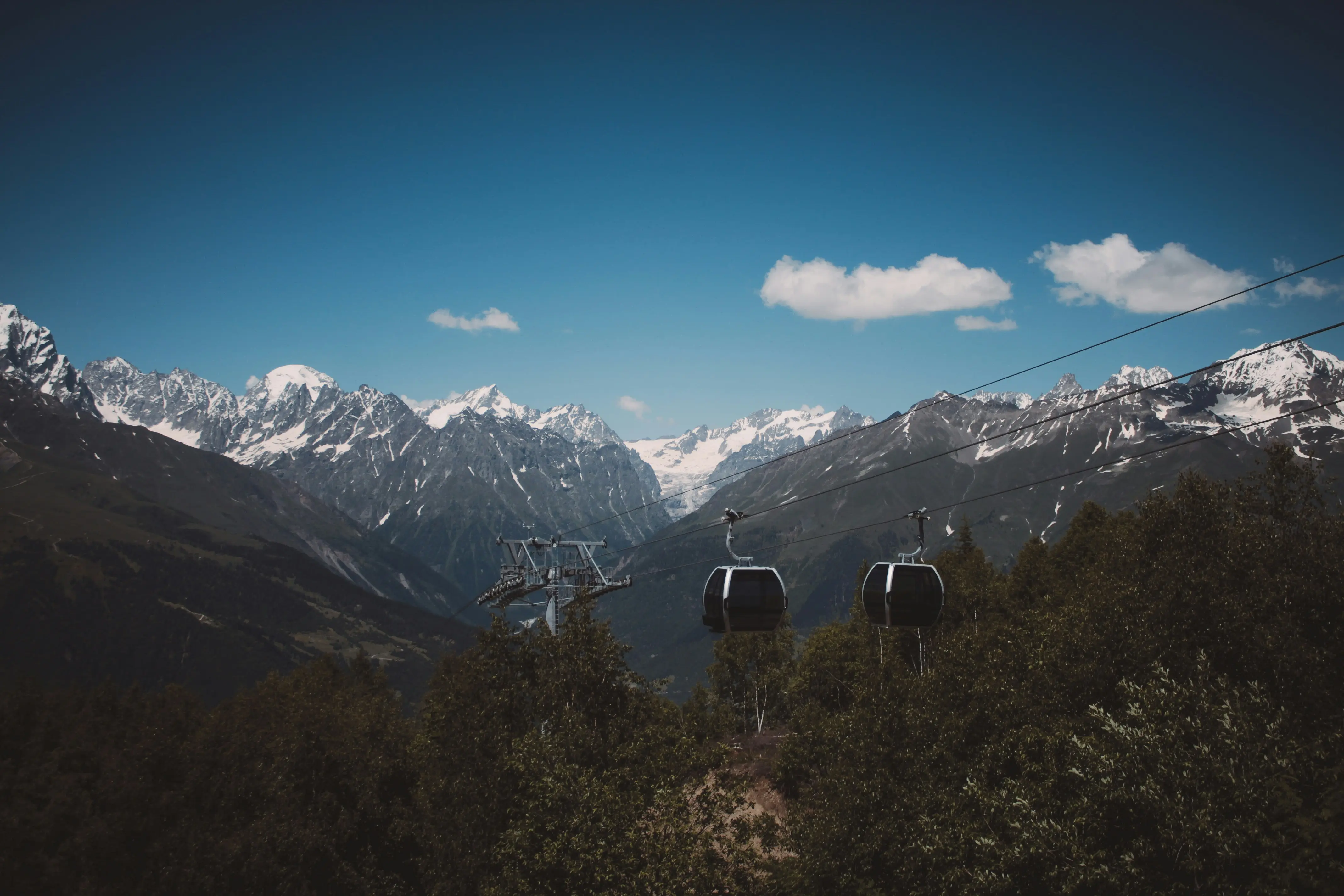 Wide shot of cable cars in the summer day with mountains in the background